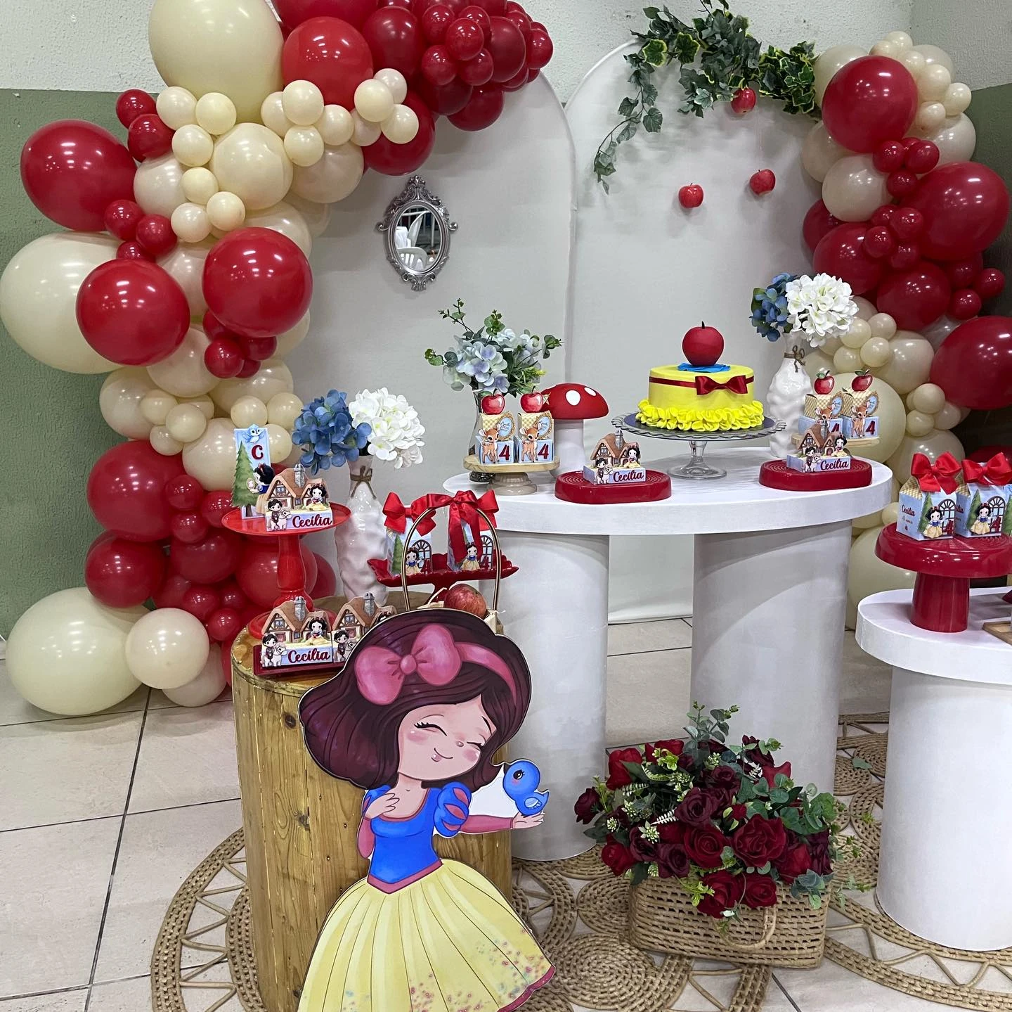 Festa infantil Branca de Neve com balões vermelhos e creme, maçãs e mesas decoradas.